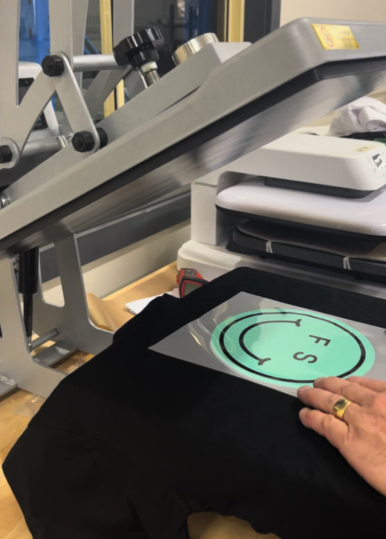 Heat press with a t-shirt and smiley face DTF transfer on it