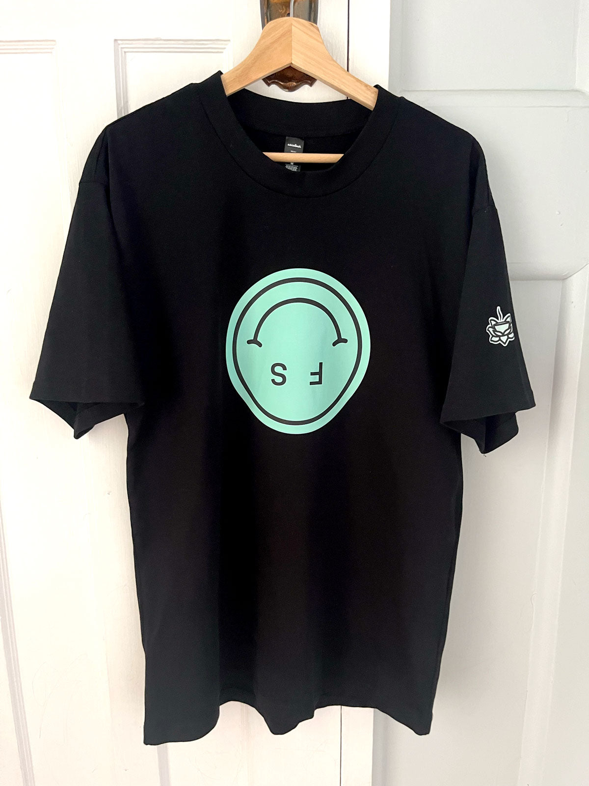 Black t-shirt with green printed smiley face on it