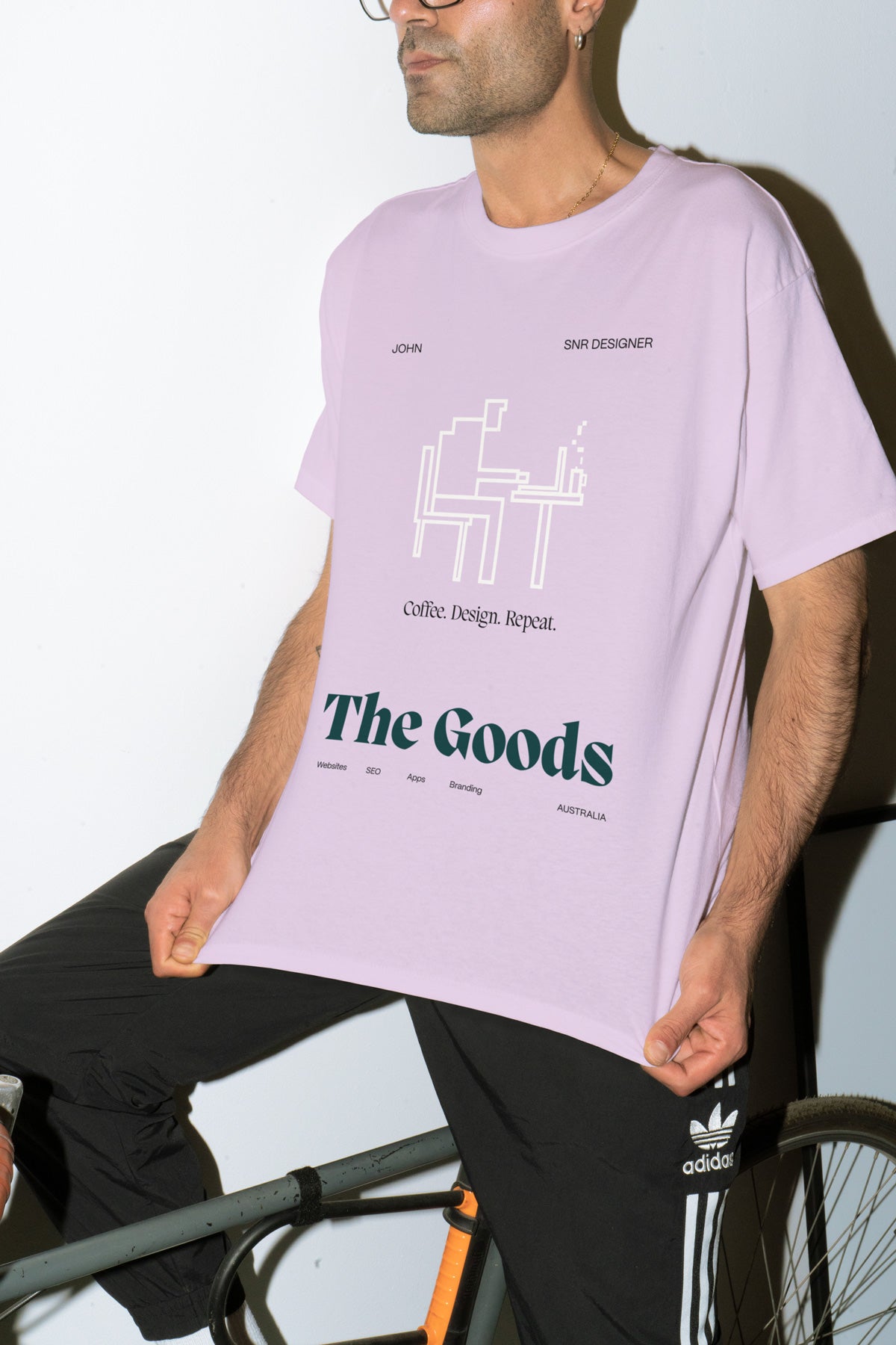 Man holding out his shirt that is printed with The Goods logo