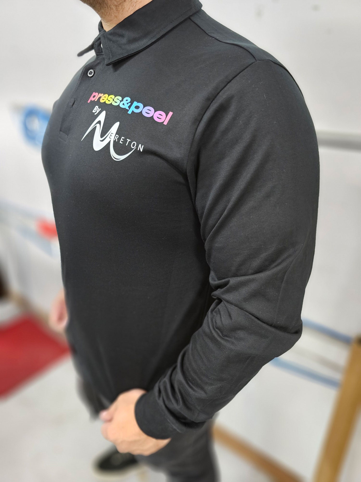 Man standing, wearing a black shirt that says "Press&Peel"