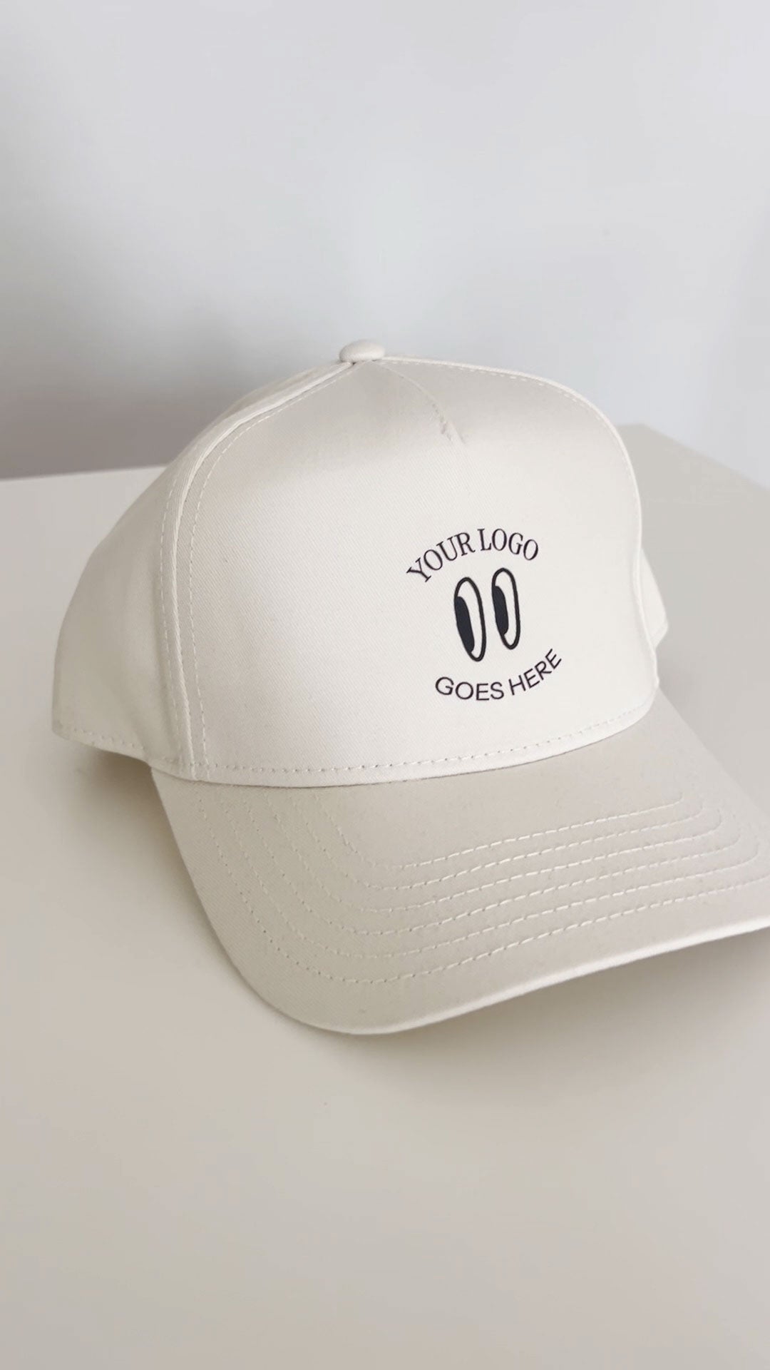 A beige hat with "your logo here" DTF transferred on it