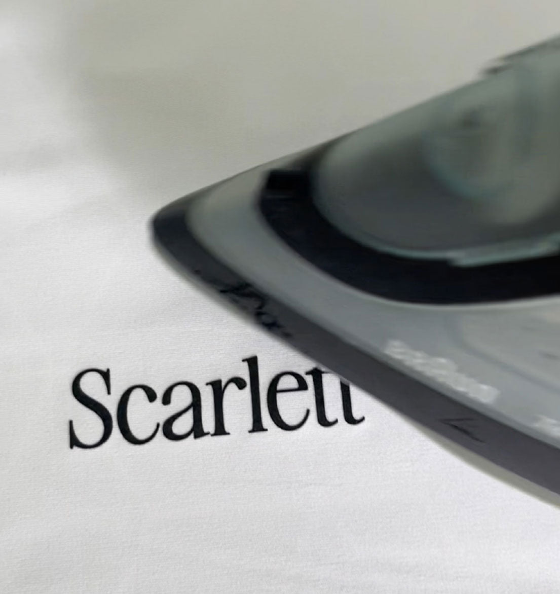 White fabric with a DTF transfer on it that says "Scarlett" being ironed on