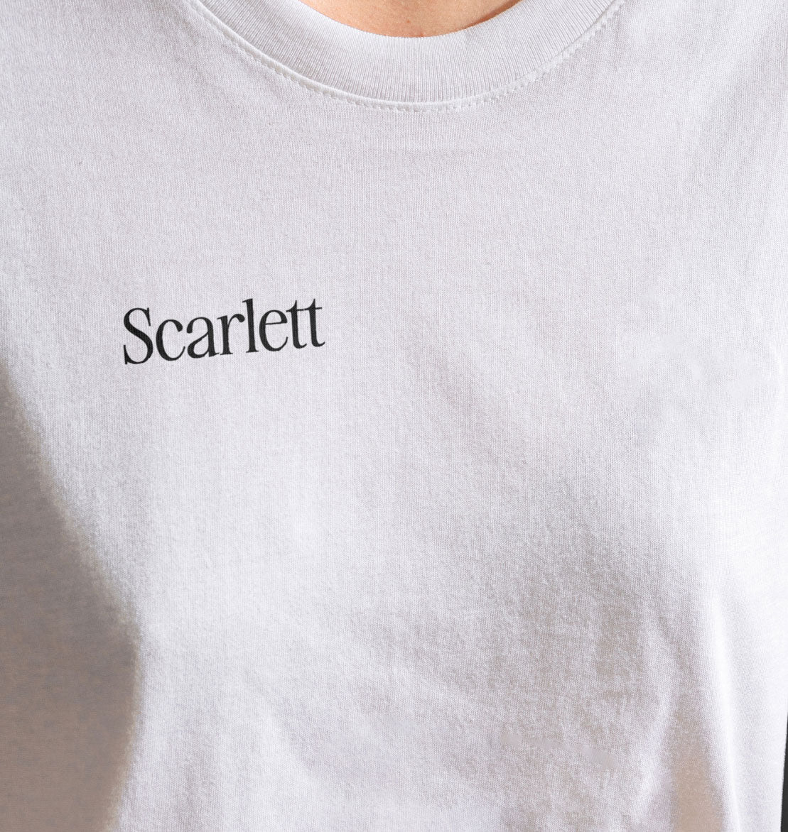 Closeup of a woman wearing a white shirt with a name badge "Scarlett" that has been DTF transferred on