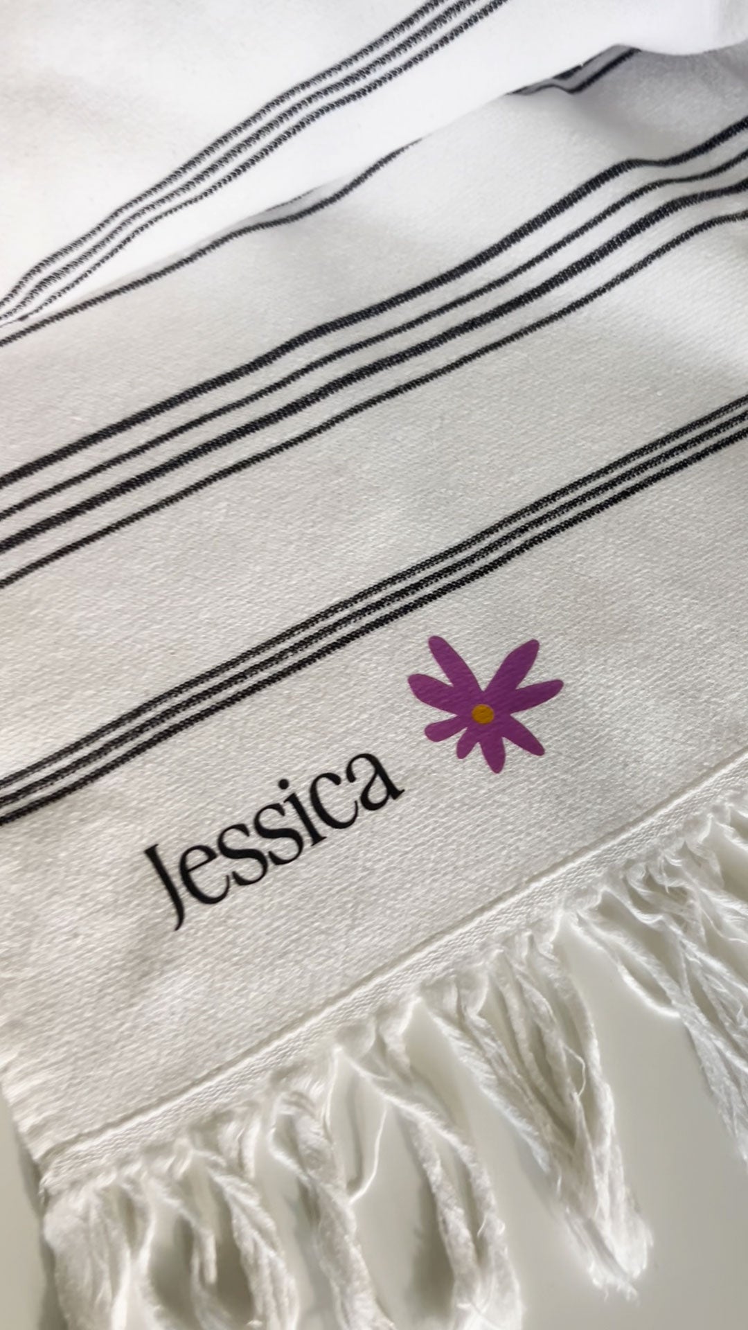 A white towel with the name "Jessica" monogrammed on it