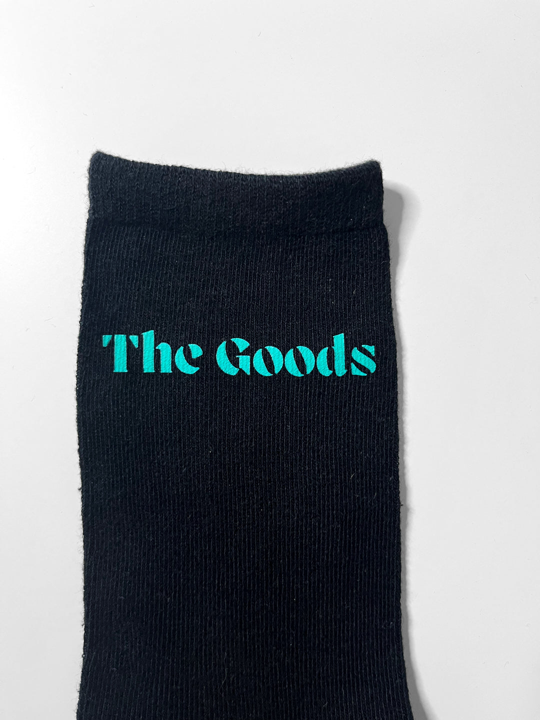 Black sock with a DTF transfer of a logo that says "The Goods"