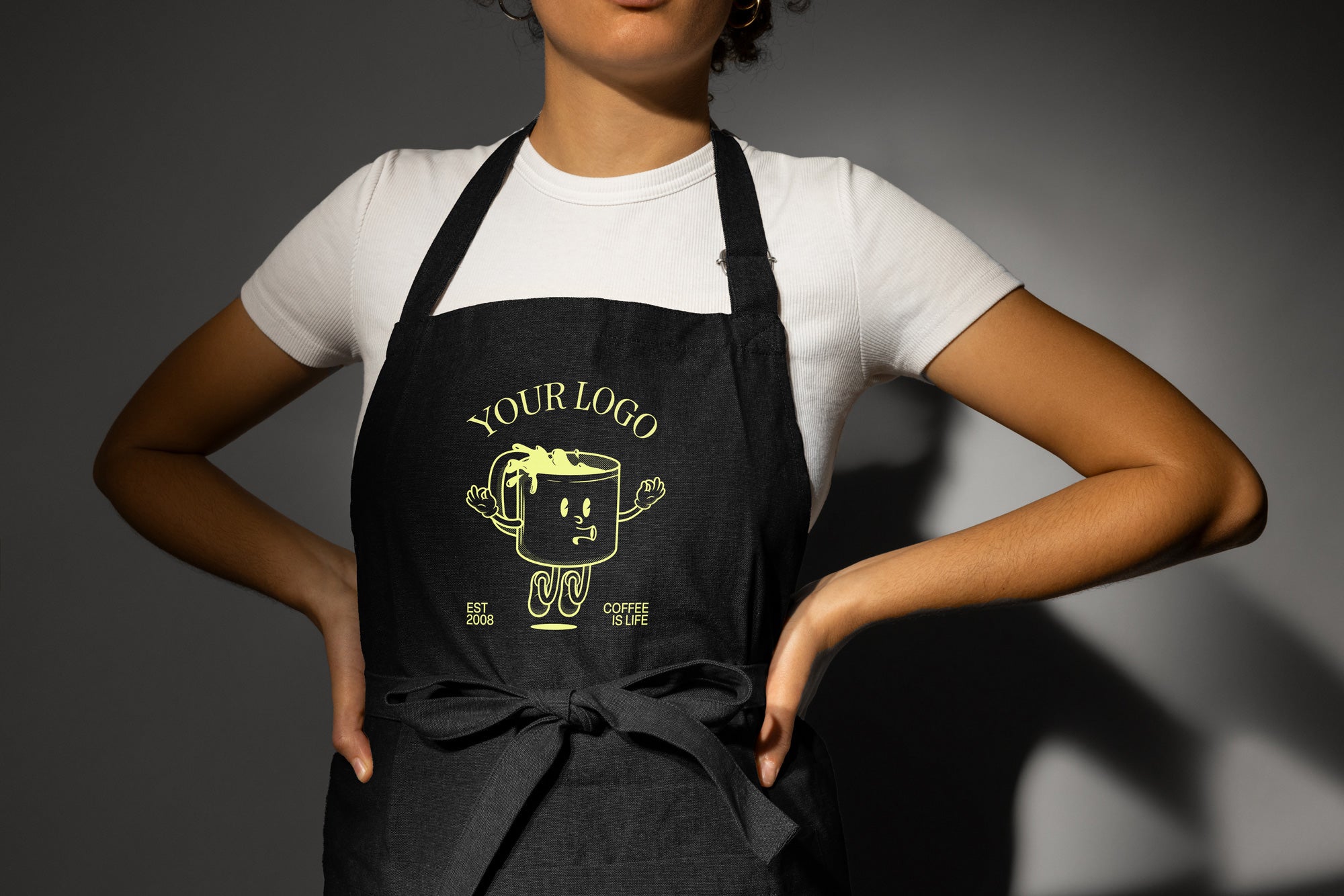 Woman wearing an apron with a DTF transfer image of a coffee cup on it that says "your logo here"