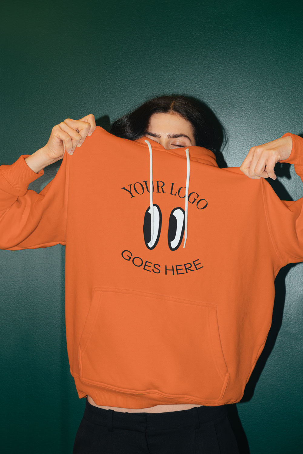 Woman wearing an orange hoodie with a DTF transfer on it that says "your logo here"